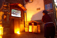 . Ieille Naxi woman in front of a flat screen installed by the city