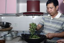 Mr. Luo Hou You travaillant des feuilles de thé fraichement achetés dans sa cuisine