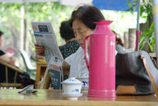 Szechuan reading a newspaper in a tea outdoors